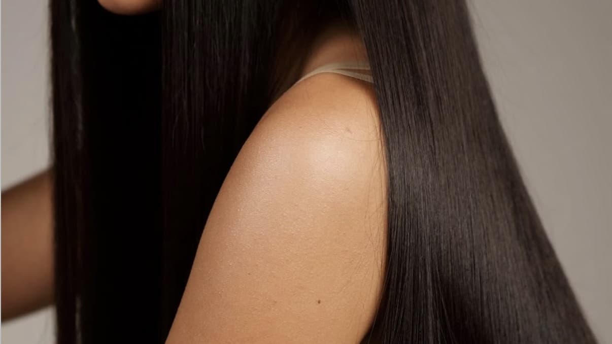 Long dark hair worn straight, photographed from the side against a neutral backdrop