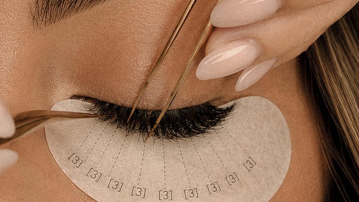 Lash extensions being applied with isolation tweezers over a mapped under-eye pad at UNIQUE PERSONA Dubai
